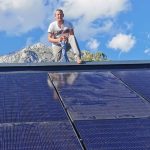Markus Aichholzer ein mann sitzt auf dem giebel eines hausdachs, auf dem eine neu installierte photovoltaik-anlage zu sehen ist